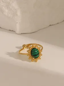 Gros plan détaillé d'une bague ajustable dorée ornée d'une pierre de malachite verte striée