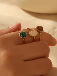 Dettaglio di anelli vintage dorati con malachite, madreperla e pietre occhio di tigre