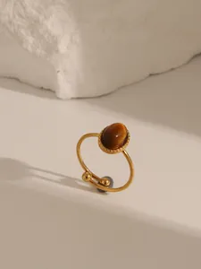 Dettaglio dell'anello vintage dorato con pietra occhio di tigre ovale e bordi con perline