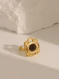 Macro shot of vintage gold-plated open ring with retro hollow design and brown stone inlay