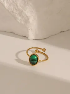 Dettaglio anello aperto dorato con pietra di malachite verde e bordo perlato