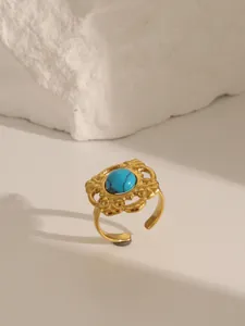 Detail of vintage gold stainless steel ring featuring turquoise stone and hollow pattern