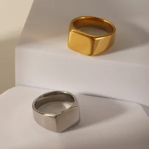 Polished gold and silver stainless steel signet rings on white geometric stands