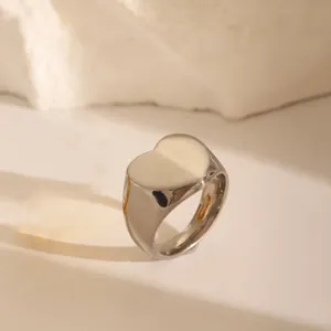 Close-up of heart-shaped stainless steel signet ring on textured stone surface