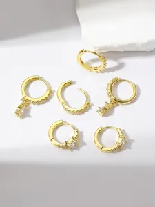 Six minimalist gold hoop earrings set with cubic zirconia on a neutral background