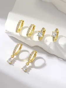 Detailed close-up of a three-piece gold earring set with square and pear-cut crystals