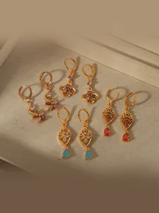 Detail view of four pairs of vintage gold earrings with colorful gemstones on a tray