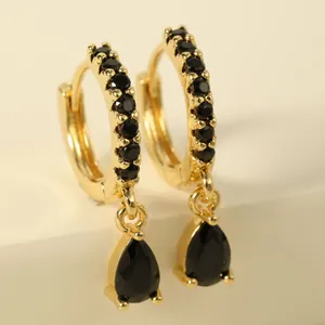 Macro view of gold hoop earrings featuring black pavé gems and pear-cut drop stones