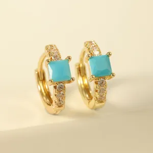 Detail of gold hoop earrings featuring square turquoise stones and micro-pave zircons