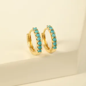Detailed macro view of gold-plated hoop earrings featuring inlaid turquoise stones