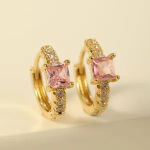 Close-up of gold hoop earrings with square pink gemstone and sparkling clear crystals