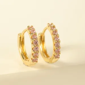 Close-up of gold-plated huggie earrings featuring seven inlaid pink round zircons