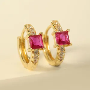 Detailed close-up of golden hoop earrings featuring a square red gemstone and pavé zircon