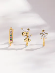Detail of three gold ear cuffs featuring rainbow gemstones and zircon flower designs