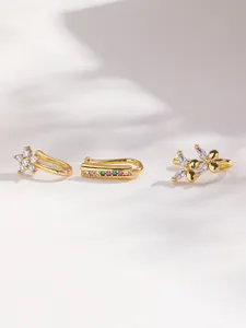 Detailed view of three gold ear cuffs featuring floral, butterfly and rainbow gem motifs