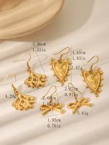 Detailansicht goldener Ohrringe mit Herz-, Schleifen- und Korallenblatt-Designs