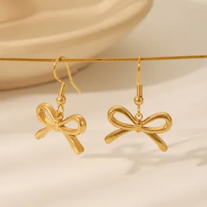 Elegante goldene Schleifenohrringe mit mattem Finish und Ohrhaken-Design auf Keramik