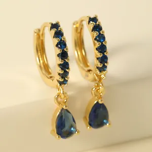 Close-up of golden hoop earrings with dark blue crystals and water drop pendants