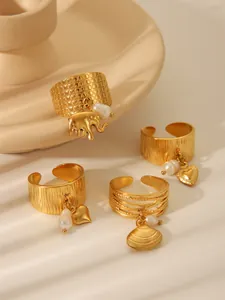 Macro detail of gold adjustable rings featuring elephant, heart, and shell pendants with pearls