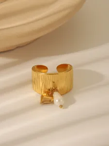 Close-up detail of a textured gold stainless steel ring with pearl and heart pendants