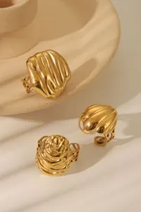 Detailed view of three textured gold stainless steel rings on a beige ceramic tray