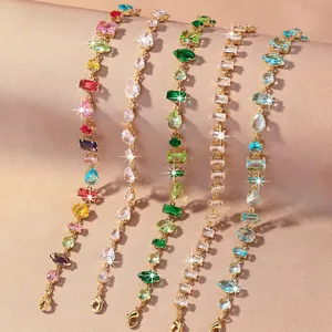 Elegante vergoldete Kupferarmbänder mit bunten Zirkonsteinen auf Seidenhintergrund