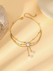 Détail de la chevillère dorée double épaisseur avec fleur blanche et perles élégantes