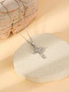 Close-up detail of the dazzling diamond-inlaid cross necklace with elegant crown design.
