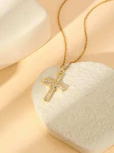 Close-up of a gold-plated cross pendant necklace featuring sparkling cubic zirconia stones.