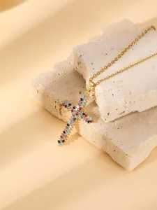 Detailed close-up of a gold-plated cross pendant necklace with colorful sparkling pavé crystals.