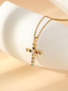 Close-up detail shot of a gold plated stainless steel cross pendant necklace with colorful stones.