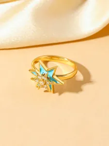 Detail of gold-plated star ring featuring blue enamel inlay and a sparkling white zircon