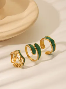 Detail of vintage gold-plated rings with green enamel and irregular wave design