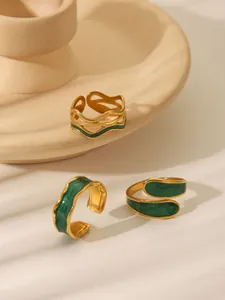 Macro shot of three vintage gold-plated rings with green enamel on a ceramic tray