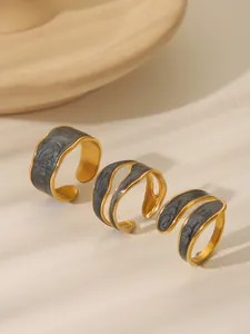 Detailed view of three gold-plated irregular rings with grey marble enamel inlay