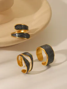 Detail of vintage gold open rings with grey marble enamel and irregular edges on ceramic