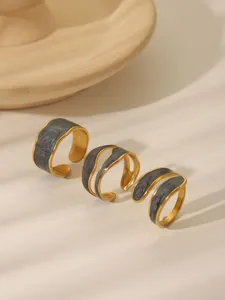 Detailed close-up of retro gold-plated rings with dark marble drip oil in shadow lighting