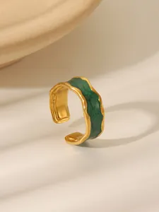 Detail of vintage irregular gold ring with green enamel and lava texture