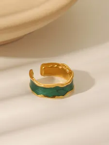 Macro detail of gold-plated wavy ring with dark green enamel and open adjustable band
