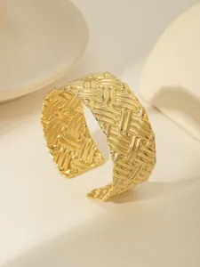 Dettaglio macro della trama intrecciata e placcatura oro 18k sul bracciale rigido aperto