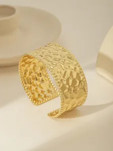Dettaglio del bracciale rigido in acciaio placcato oro 18k con trama martellata e bordi perlati