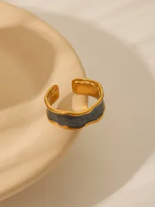 Macro detail of a gold adjustable ring with irregular edges and dark gray enamel inlay