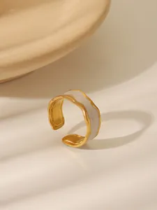 Detail of gold open ring with irregular wavy edges and white enamel inlay finish