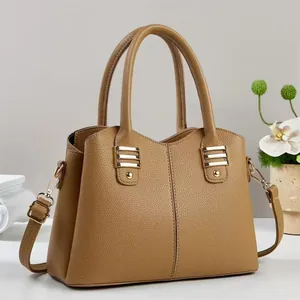 Detail of a brown leather tote bag with gold hardware and removable shoulder strap