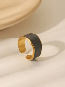 Detail of wide gold adjustable ring featuring a grey marble enamel inlay and irregular edges