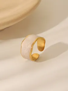 Detail of vintage gold-plated ring with white enamel inlay and irregular wave edges