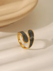 Macro detail of golden bypass ring with marble enamel inlay on a textured tray