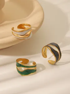 Detailed view of three gold ripple rings with white, green, and grey enamel inlay
