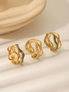 Detail view of wavy gold rings with drip oil enamel in grey, white, and emerald green