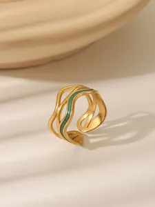 Detailed macro of matte gold ring with green enamel inlay and wave patterns